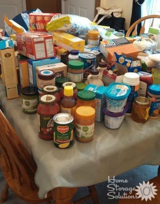 Food all pulled from the pantry and placed onto kitchen table for sorting and decluttering {featured on Home Storage Solutions 101}