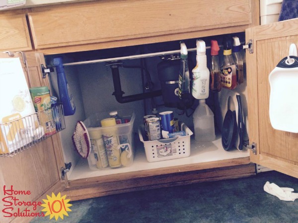 Use a tension rod under your kitchen sink to hang spray bottles for easy organization {featured on Home Storage Solutions 101}